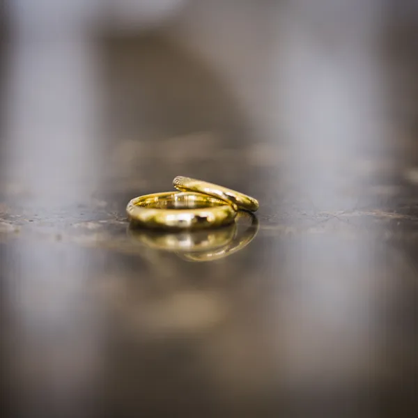 Paar handgemaakte trouwringen in goud, naast elkaar op leisteen